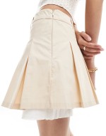 pleated mini skirt with white layered raw hem detail in beige